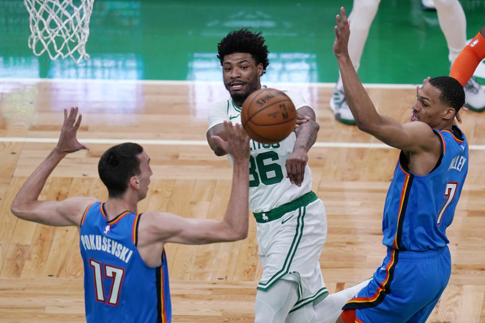 Boston Celtics guard Marcus Smart, center, passes the ball while trapped by Oklahoma City Thunder's Aleksej Pokusevski, left, and Darius Bazley, right, during the first half of an NBA basketball game, Tuesday, April 27, 2021, in Boston. (AP Photo/Charles Krupa)