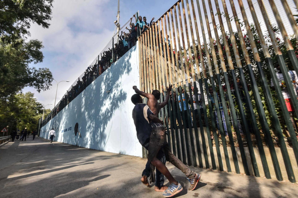 <p>A man holds a fellow migrant who got injured while forcing their way into the Spanish territory of Ceuta on August 22, 2018. – Over 100 migrants made their way into Ceuta after storming a barbed-wire border fence with Morocco and attacking police with caustic quicklime, a local official said. (Photo by JOAQUIN SANCHEZ/AFP/Getty Images) </p>