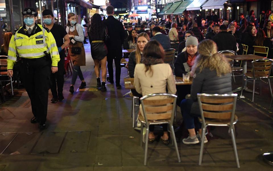 Police officers walk past drinkers in Soho, central London after the introduction of the 10pm curfew last week - Peter Summers/ Getty Images Europe