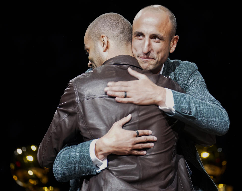 Former San Antonio Spurs guard Manu Ginobili, right, hugs former teammate Tony Parker during Ginobili's retirement ceremony after the team's NBA basketball game against the Cleveland Cavaliers, Thursday, March 28, 2019, in San Antonio. San Antonio won 116-110. (AP Photo/Darren Abate)