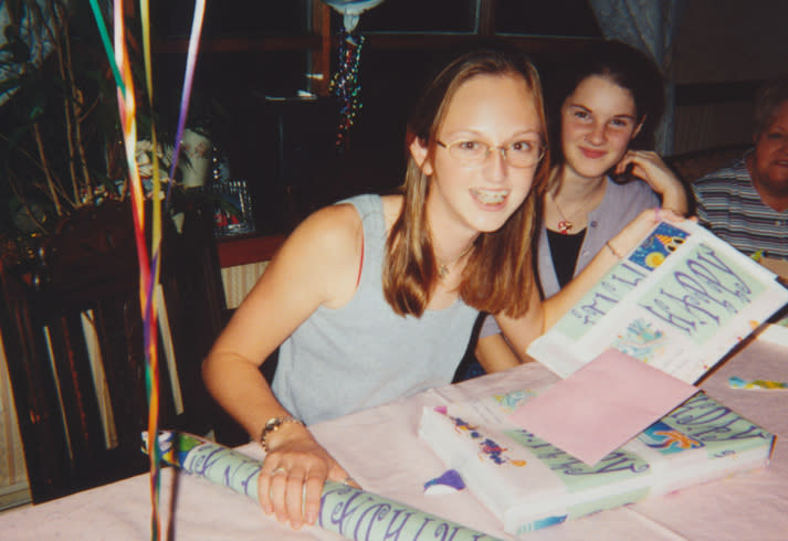 Two people smiling at a birthday party with a cake and gifts, having a joyful time