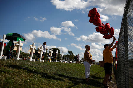 Susan Glaser-Cohen (C) mourns while she stands between the fence of the Marjory Stoneman Douglas High School and crosses placed to commemorate the victims of a mass shooting in Parkland, Florida, U.S., February 18, 2018. REUTERS/Carlos Garcia Rawlins