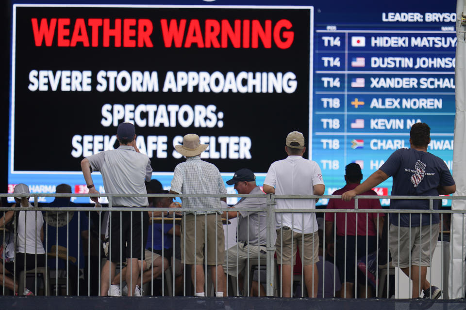 Los espectadores se refugian debajo de una carpa durante la interrupción del BMW Championship por la lluvia, el viernes 27 de agosto de 2021, en Owing Mills, Maryland (AP Foto/Julio Cortez)