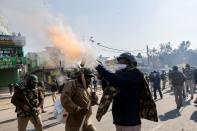 A police officer fires tear gas to stop farmers opposing the newly passed farm bills from entering the national capital Delhi, at Singhu border, India