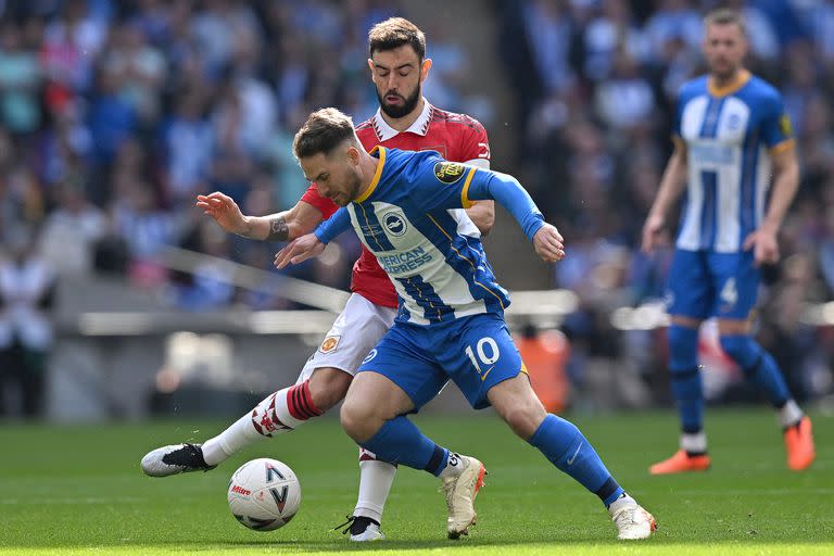 Alexis Mac Allister cubre la pelota ante la carga de Bruno Fernandes, en un Brighton vs. Manchester United; en la próxima temporada también él vestiría una camiseta roja, pero la de Liverpool.