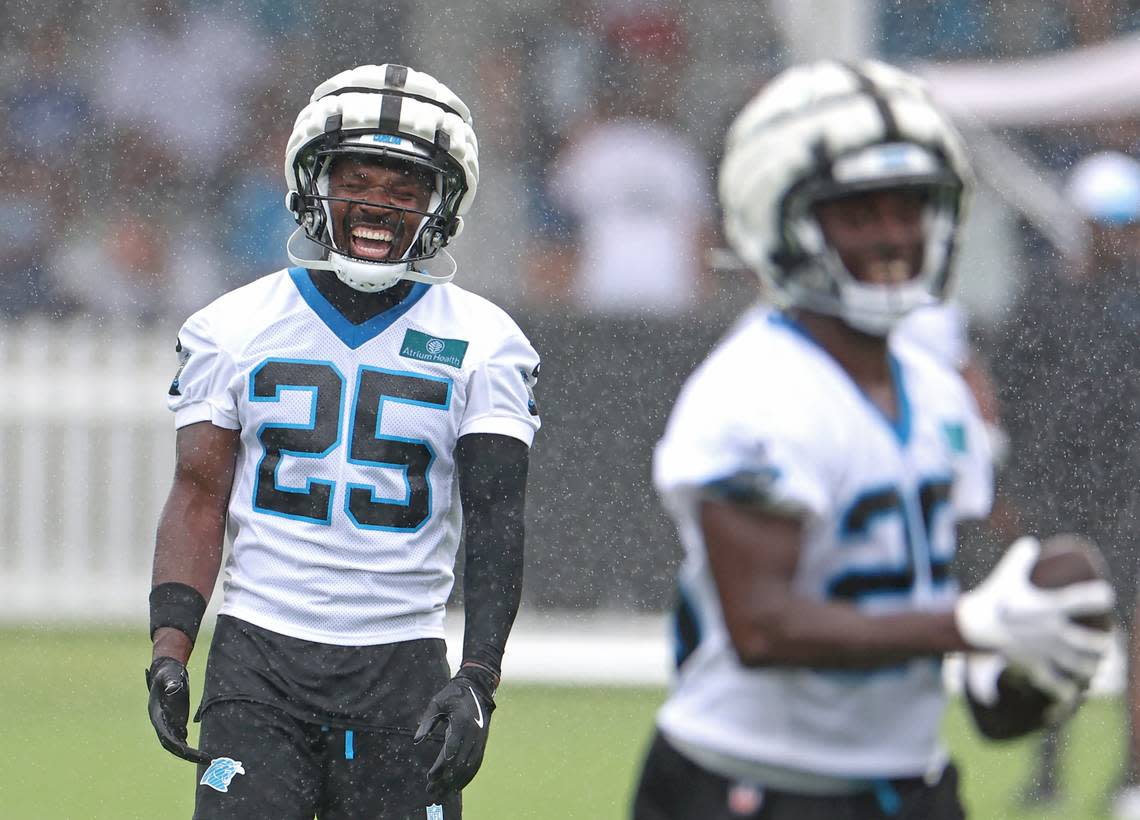 Carolina Panthers safety Xavier Woods, left, does not let the falling rain dampen his mood during practice on Thursday, July 25, 2024.