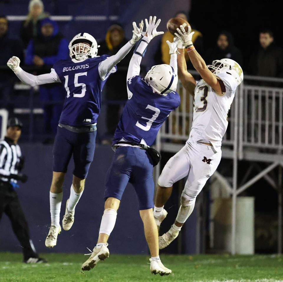 Millbury receiver George Andrianopoulos makes the catch over Rockland defenders from left, Jax Leduc and Tyler Boehner during a game on Friday, Nov. 3, 2023.