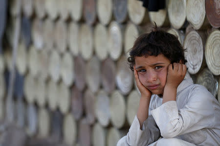 A boy looks on as he sits next to a hut at a camp for people displaced by the war near Sanaa, Yemen April 24, 2017. REUTERS/Khaled Abdullah