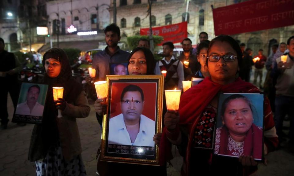 Survivors and relatives of victims of the Bhopal gas accident hold photos of the victims during a candlelight vigil.