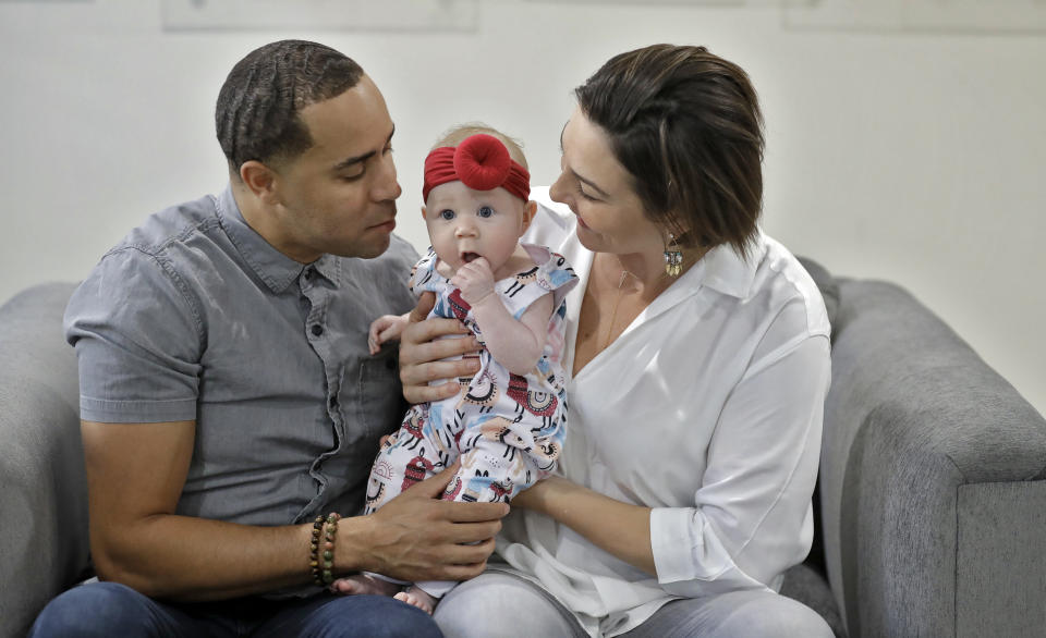 NBA referees Jonathan Sterling, left, and Lauren Holtkamp-Sterling, the only married couple in NBA refereeing history, pose for a photo with their daughter Stoan at their home Thursday, Oct. 3, 2019, in Tampa, Fla. (AP Photo/Chris O'Meara)