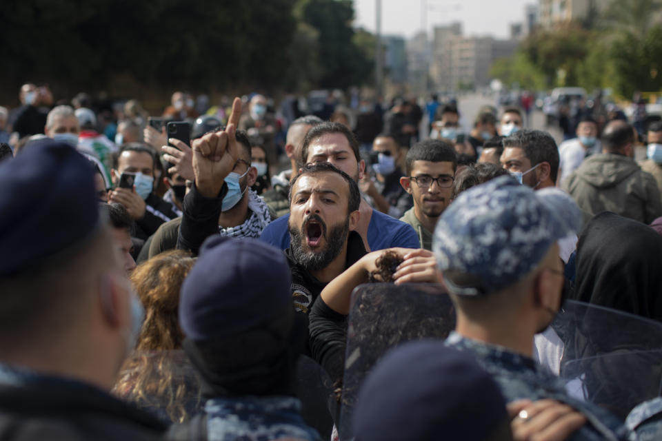 An anti-government protester shouts slogans outside a military court, in Beirut, Lebanon, Monday, Feb. 8, 2021. Riot police briefly clashed Monday in Beirut with hundreds of protesters demanding the release of anti-government activists detained following riots in northern Lebanon late last month. (AP Photo/Hassan Ammar)