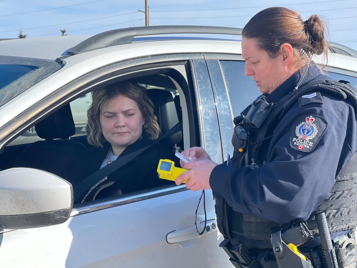 A Regina Police Service officer conducts a demonstration of a breathalyzer test. Police in the city are launching a new initiative requiring any driver to do an alcohol screening test, no matter the reason they are pulled over. (Darla Ponace/CBC - image credit)