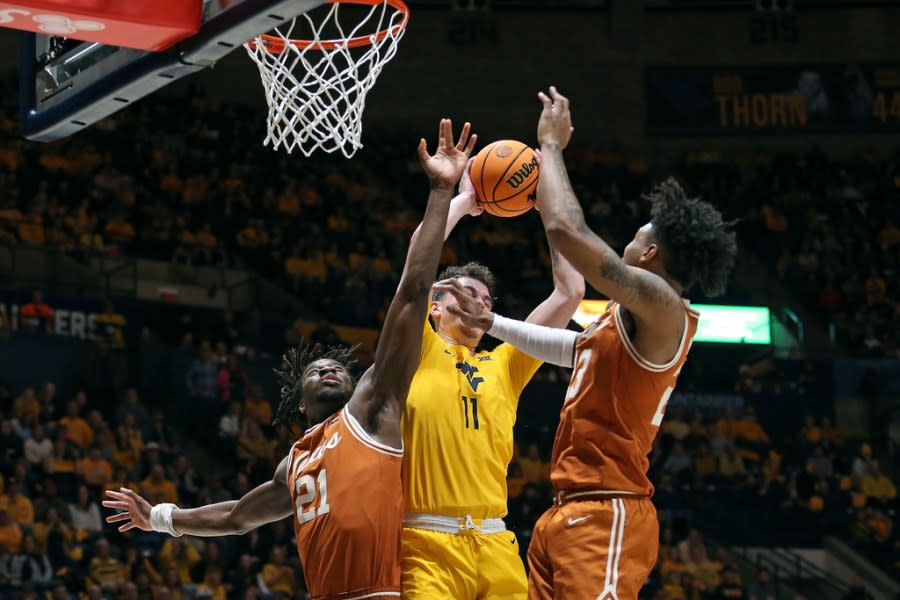 West Virginia forward Quinn Slazinski (11) is defended by Texas forwards Ze’Rik Onyema (21) and Dillon Mitchell (23) during the second half of an NCAA college basketball game on Saturday, Jan. 13, 2024, in Morgantown, W.Va. (AP Photo/Kathleen Batten)