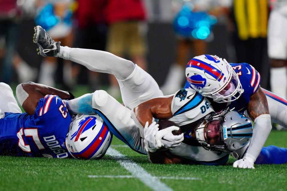 El corredor de los Carolina Panthers, Chuba Hubbard, es derribado por el apoyador de los Buffalo Bills, Tyrel Dodson, y el apoyador Terrel Bernard, durante la primera mitad de un partido de pretemporada de la NFL el viernes, 26 de agosto de 2022, en Charlotte, Carolina del Norte (AP Photo/Jacob Kupferman)