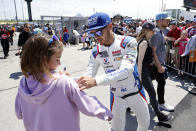 Kyle Larson, center, signs autographs a he heads to pit road before the start of a NASCAR Cup Series auto race at Kansas Speedway in Kansas City, Kan., Sunday, May 15, 2022. (AP Photo/Colin E. Braley)