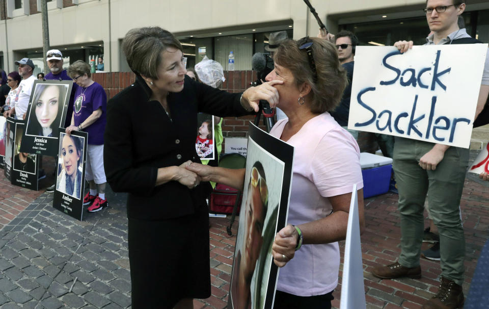 Massachusetts Attorney General Maura Healey, left, wipes a tear from the face of Wendy Werbiskis, of East Hampton, Mass., one of the protesters gathered on Friday, Aug. 2, 2019, outside a courthouse in Boston, where a judge was to hear arguments in state's lawsuit against Purdue Pharma over its role in the national drug epidemic. Organizers said they wanted to continue to put pressure on the Connecticut pharmaceutical company and the Sackler family that owns it. Werbiskis lost her son to an overdose two years ago. (AP Photo/Charles Krupa)