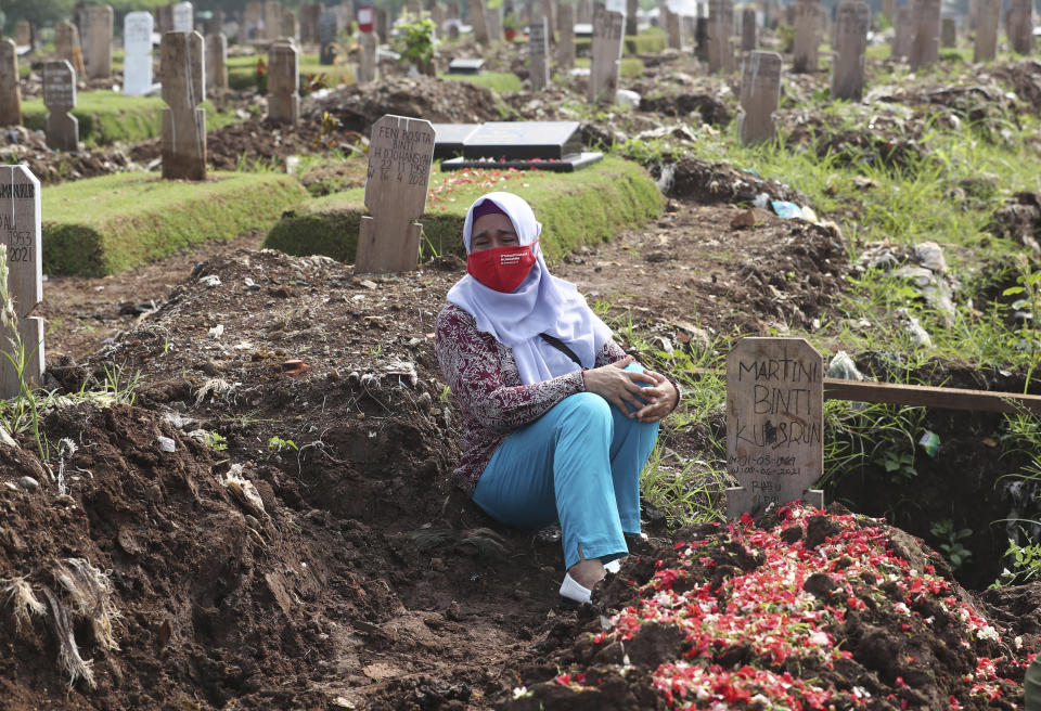 A family member reacts during the burial of her relative at a section of Srengseng Sawah Cemetery reserved for those who died of COVID-19, in Jakarta, Indonesia, Wednesday, June 9, 2021. The world's fourth-most populous country, with about 275 million people, has reported more coronavirus cases than any other Southeast Asian country.(AP Photo/Tatan Syuflana)