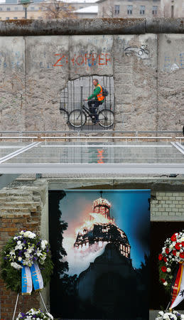 A cyclist passes behind remains of the Berlin Wall at the Topography of Terror museum located at the site of the former Nazi Gestapo and SS headquarters, as Germany marks the 80th anniversary of Kristallnacht, also known as Night of Broken Glass in Berlin, Germany, November 9, 2018. REUTERS/Fabrizio Bensch