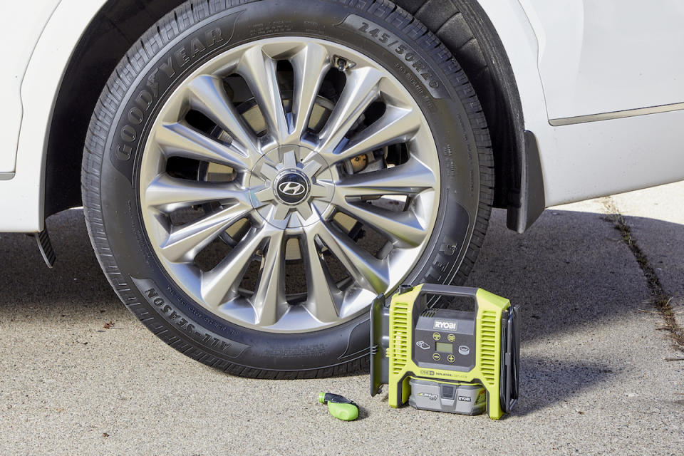 View of one tire on car, along with tire pressure gauge and inflating apparatus.