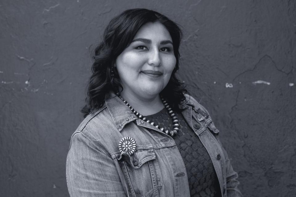 A woman in a denim shirt with a beaded necklace