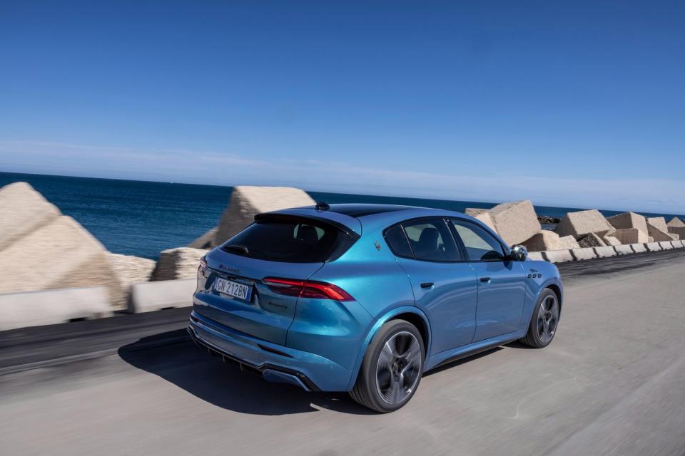 a blue 2025 maserati grecale folgore parked on a road near a body of water