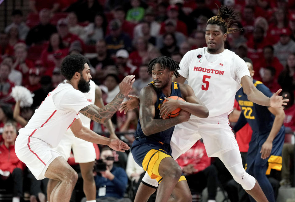 West Virginia guard Kobe Johnson, center, is pressured by Houston forward Ja'Vier Francis (5) and guard Damian Dunn during the first half of an NCAA college basketball game Saturday Jan. 6, 2024, in Houston. (AP Photo/Eric Christian Smith)
