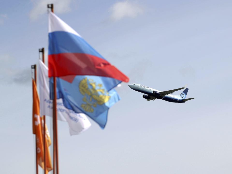 Private jet takes off from airport in Siberia, Russia, behind Russian flags