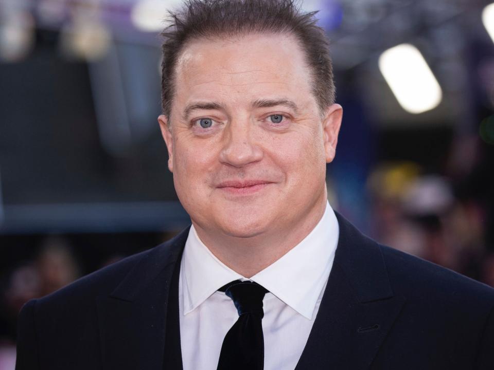 Brendan Fraser poses for photos on the red carpet in a black suit and white shirt.