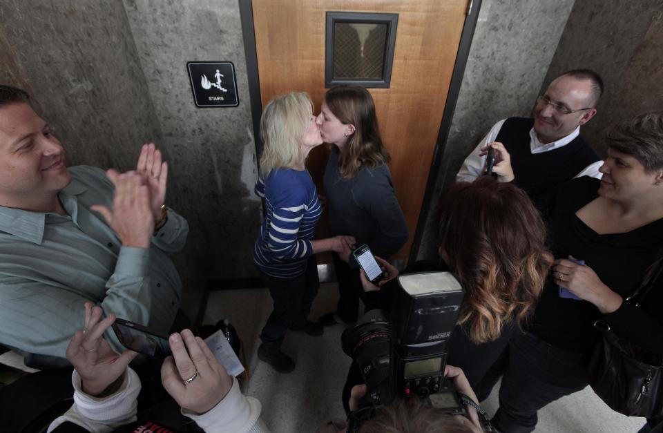 FILE - In this March 22, 2014 file photo Elizabeth Gardiner, left, and Stephanie Citron kiss after being married in a hallway at the Oakland County Clerk in Pontiac, Mich., after a federal judge has struck down Michigan's ban on gay marriage. Attorney General Eric Holder on Friday, March 28, 2014 extended federal recognition to the marriages of about 300 same-sex couples that took place in Michigan before a federal appeals court put those unions on hold. (AP Photo/Paul Sancya, File)