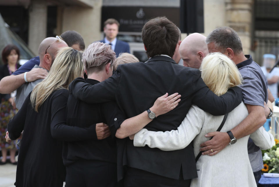 Family members of the three victims comfort each other after lighting candles during a vigil in the town of Reading, England, in memory of three people who were killed in the Reading terror attack in Forbury Gardens in the town centre. Three people were stabbed to death by a lone attacker on Saturday June 27, in what is being treated as a terror attack. (Steve Parsons/PA via AP)