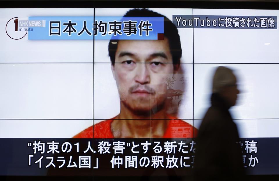 A man walks past screens displaying a television news programme showing an image of Kenji Goto, one of two Japanese citizens taken captive by Islamic State militants, on a street in Tokyo January 25, 2015. Japanese Prime Minister Shinzo Abe on Sunday called the apparent killing of Japanese captive Haruna Yukawa by Islamic State militants "outrageous and impermissible," and again called for the group to release Goto, the second Japanese national they are holding. The words on the screen read "Japanese hostage incident" (top L) and "a still image posted on YouTube" (top R). REUTERS/Yuya Shino (JAPAN - Tags: POLITICS CIVIL UNREST MEDIA HEADSHOT TPX IMAGES OF THE DAY CRIME LAW)