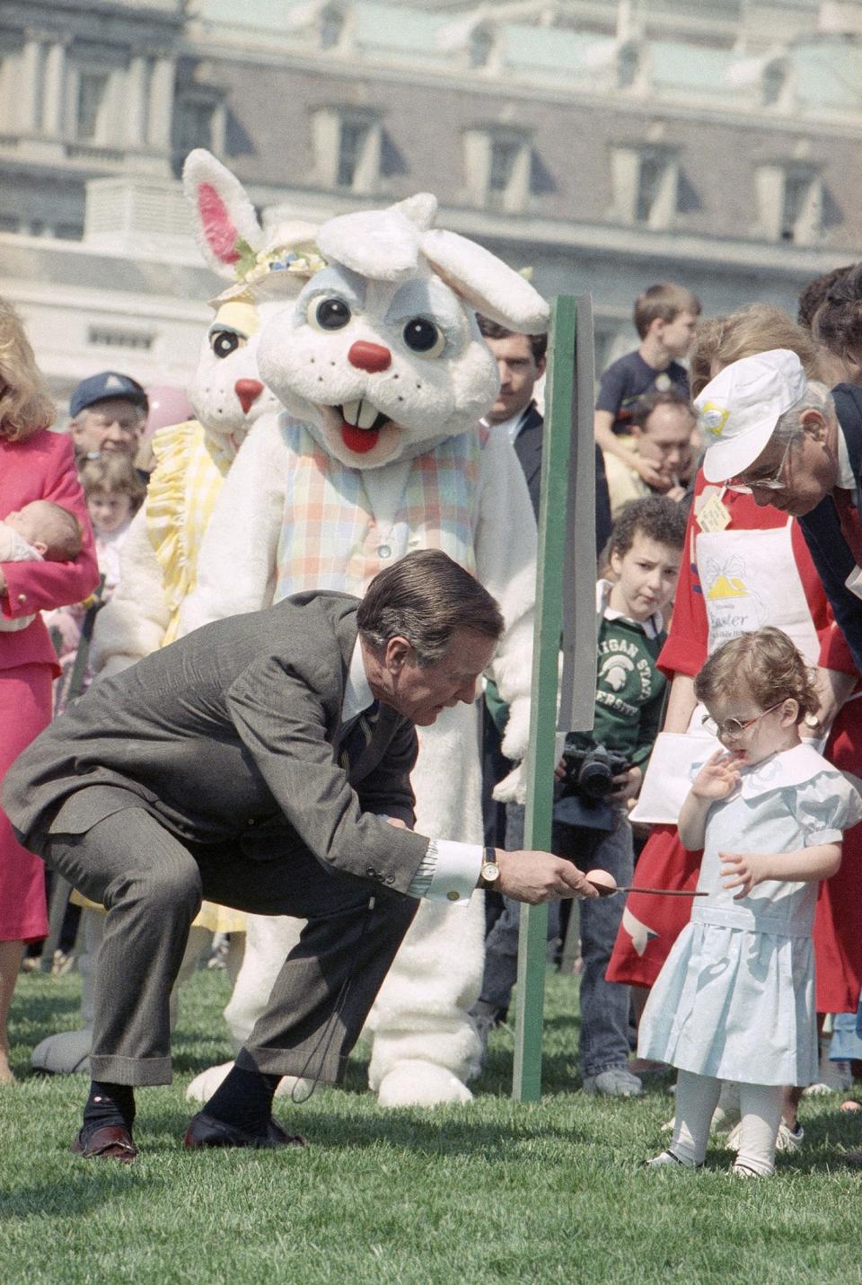 <p>President George H.W. Bush bends down and gives his granddaughter, Ellie LeBlond, instructions on how to roll an egg at the lllth annual Easter Egg Roll that took place, Monday, March 27, 1989 on the South Lawn of the White House in Washington. (Photo: Dob Daugherty/AP) </p>