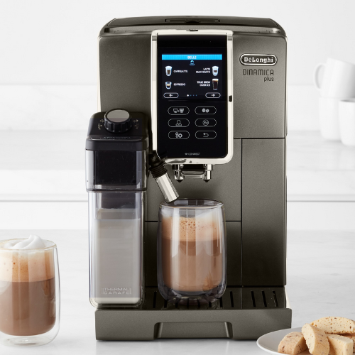 coffee maker on kitchen counter top with two cups of coffee and cookies in a bowl