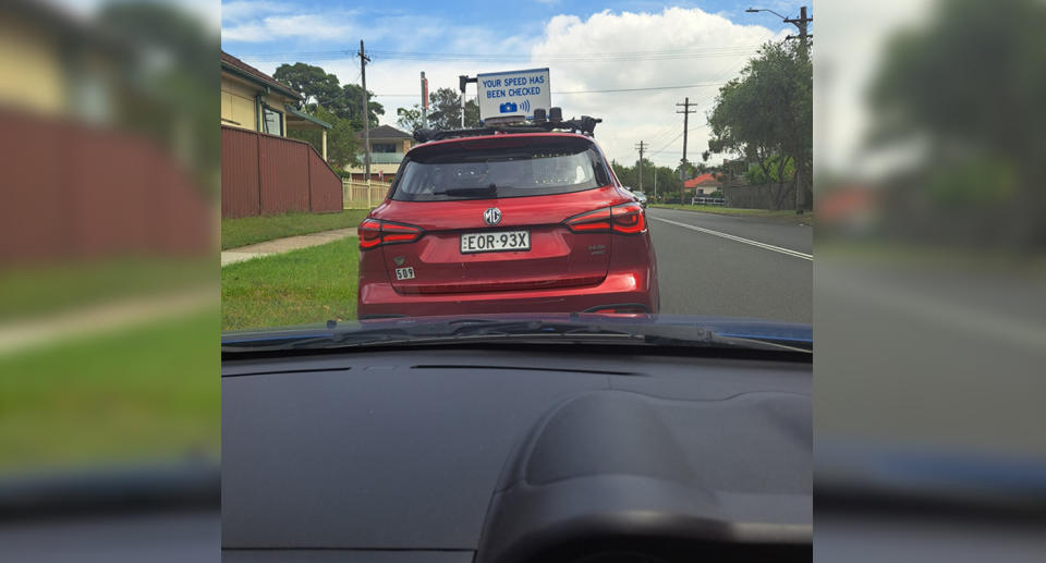 Red unmarked mobile speed camera vehicle parked on side of the road. 