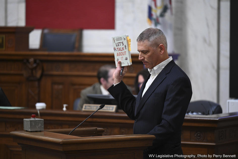 West Virginia resident Jeff Smith holds up the book "Let's Talk About it: The Teen's Guide to Sex, Relationships and Being Human" as an example of obscene material that should not be legally protected by public libraries and schools during a public hearing on proposed obscenity legislation at the West Virginia State Capitol in Charleston, W.Va., on Wednesday, Jan. 24, 2024. (Perry Bennett/West Virginia Legislative via AP)