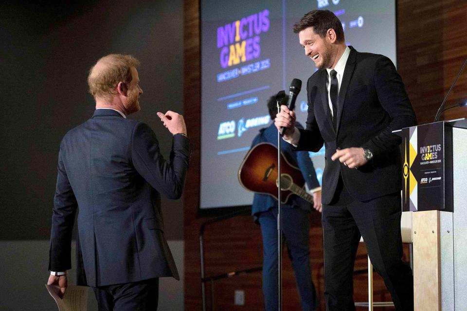 <p>Ethan Cairns/The Canadian Press via AP</p> Michael Bublé talks to Prince Harry after performing at the "One Year to Go" Invictus Games dinner in Vancouver, British Columbia in February 2024