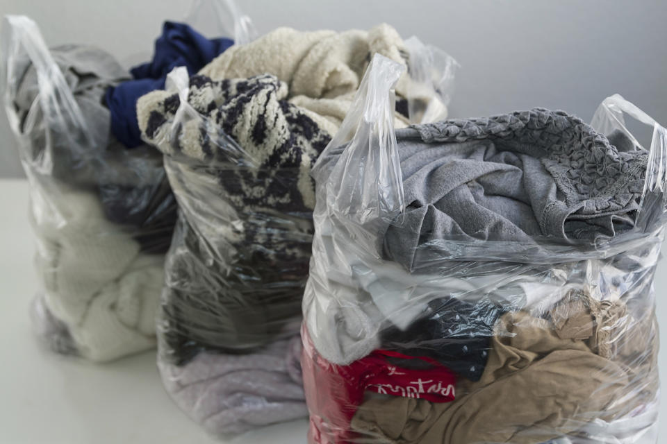 Three clear plastic bags stuffed with unwanted clothing