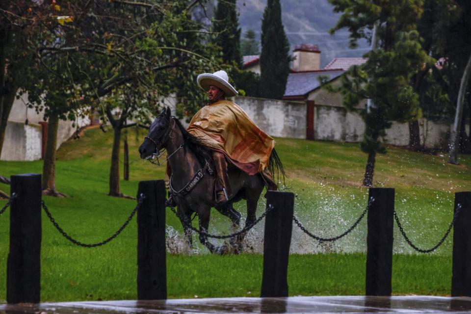 Gilberto Bueno exercises a mare through a Duarte neighborhood as heavy rains pelt the region.
