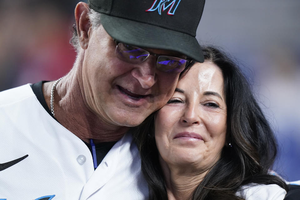 Don Mattingly, manager de los Marlins de Miami, abraza a su esposa Lori Mattingly, durante el reconocimiento dentro del campo en la quinta entrada del juego de béisbol en contra de los Bravos de Atlanta, el miércoles 5 de octubre de 2022, en Miami. (AP Foto/Wilfredo Lee)