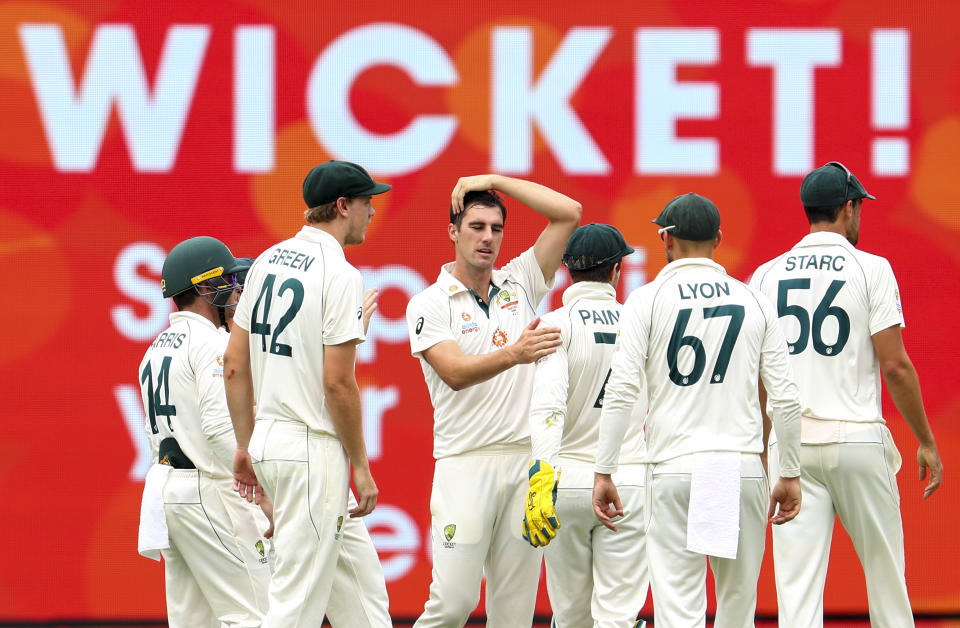 Australia's Pat Cummins, centre, celebrates with teammates after dismissing India's Rohit Sharma during play on the final day of the fourth cricket test between India and Australia at the Gabba, Brisbane, Australia, Tuesday, Jan. 19, 2021. (AP Photo/Tertius Pickard)