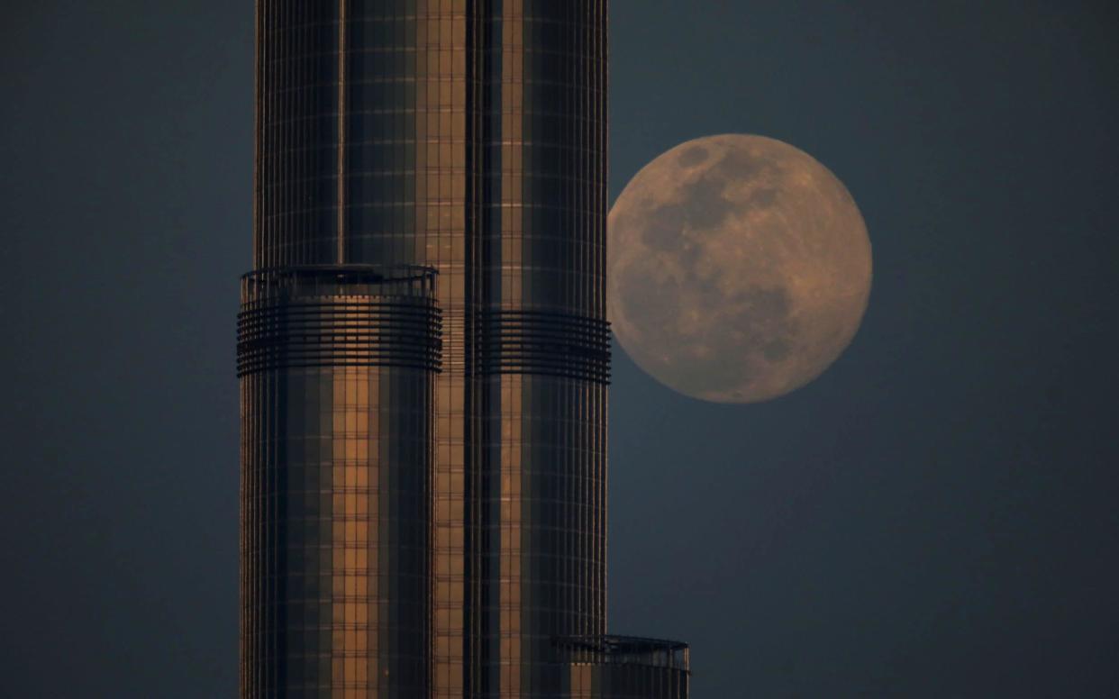 A waxing gibbous moon rises behind the Burj Khalifa, the world's tallest building, ahead of the 'Super Pink Moon', in Dubai - Reuters 