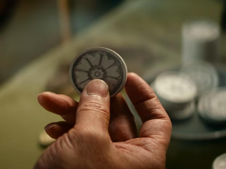 iroh holding a white lotus tile in his hand in avatar the last airbender live action