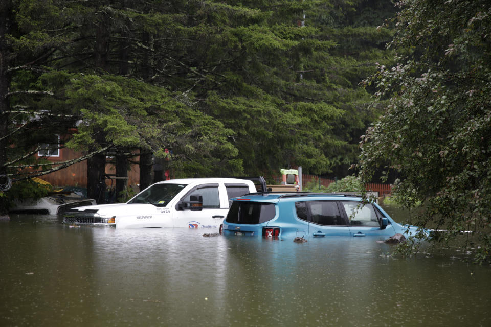 A parked truck and car have floodwaters almost up to their door handles.
