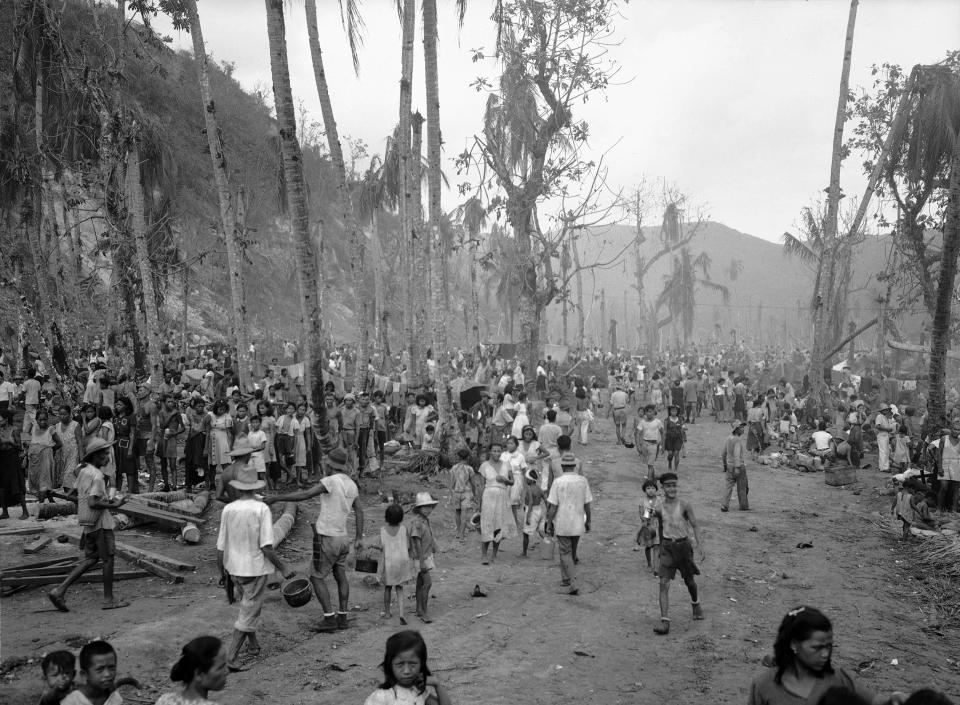 FILE - In this August, 1944 file photo, people of Guam pour out of the hills into the Agana refugee camp. The 1941 Japanese invasion of Guam, which happened on the same December day as the attack on Hawaii's Pearl Harbor, set off years of forced labor, internment, torture, rape and beheadings. More than 75 years later, thousands of people on Guam, a U.S. territory, are expecting to get long-awaited compensation for their suffering at the hands of imperial Japan during World War II. (AP Photo/Joe Rosenthal, File)