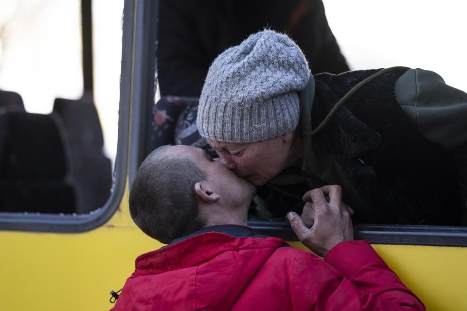 Mykolaivna Shankarukina, 54, kisses her son from inside a damaged bus as she is leaving from the Ukrainian Red Cross center in Mykolaiv, southern Ukraine, on Monday, March 28, 2022. Shankarukina and her family evacuated from Sablagodante village in the Mykolaiv district that have been attacked by the Russian army. She and a grandson are going to Odesa and from there to Prague, as the rest of the family, her son, daughter in law and a grandson will stay in Mykolaiv in a center for displaced residents. (AP Photo/Petros Giannakouris)