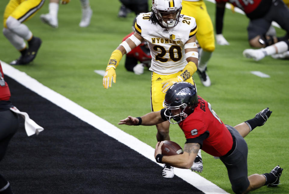 UNLV quarterback Max Gilliam (6) dives into the end zone for a touchdown ahead of Wyoming cornerback Azizi Hearn (20) during the first half of an NCAA college football game in Las Vegas on Friday, Nov. 27, 2020. (Steve Marcus/Las Vegas Sun via AP)