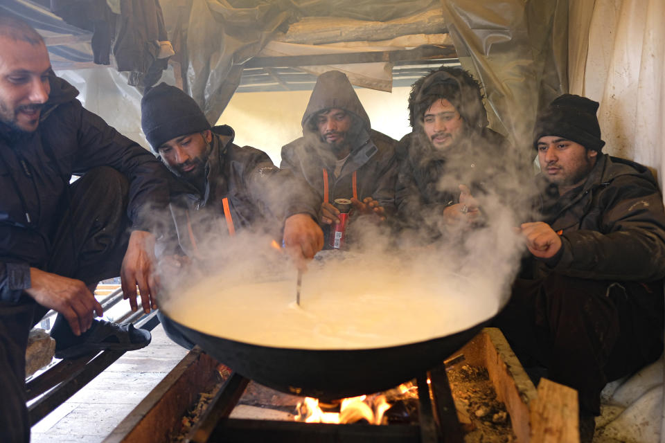 Migrants cook inside a makeshift shelter at the Lipa camp, outside Bihac, Bosnia, Friday, Jan. 8, 2021. A fresh spate of snowy and very cold winter weather on has brought more misery for hundreds of migrants who have been stuck for days in a burnt out camp in northwest Bosnia waiting for heating and other facilities. (AP Photo/Kemal Softic)