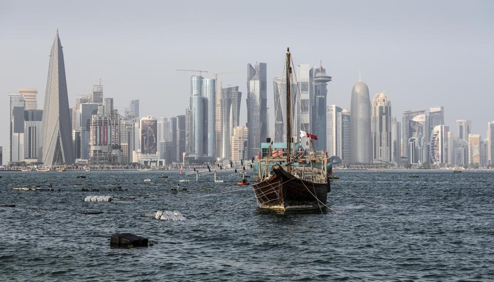 Old wooden boats anchor at the Doha Corniche in front of the modern skyline on the day before the start of the Soccer World Cup in Doha, Qatar, Saturday, Nov. 19, 2022. (AP Photo/Martin Meissner)