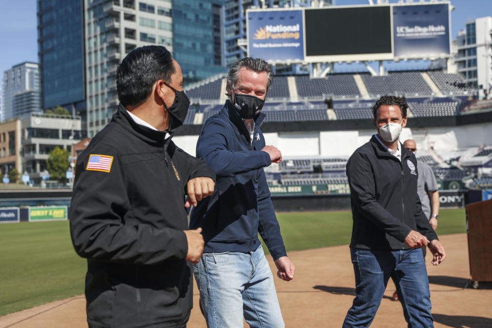 FILE - In this Feb. 8, 2021, file photo, California Governor Gavin Newsom, center, bumps elbows with San Diego Mayor Todd Gloria after a news conference at Petco Park, which will host a vaccination site in a parking lot next to the ballpark in San Diego. Newsom's weeklong tour of vaccination sites has taken on the feel of a campaign swing as the likelihood increases that he'll face a recall election. (Sandy Huffaker/The San Diego Union-Tribune via AP, Pool, File)