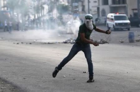 A Palestinian protester hurls stones at Israeli troops during clashes near the Jewish settlement of Bet El, near the West Bank city of Ramallah October 13, 2015. REUTERS/Mohamad Torokman